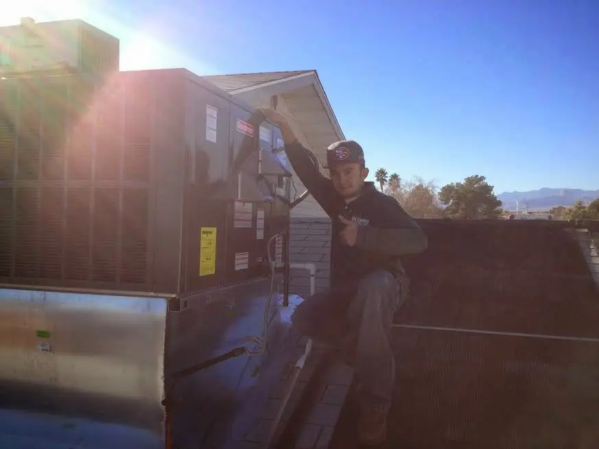 HVAC technician performing AC Tune-Up on a rooftop unit in Cedar Falls